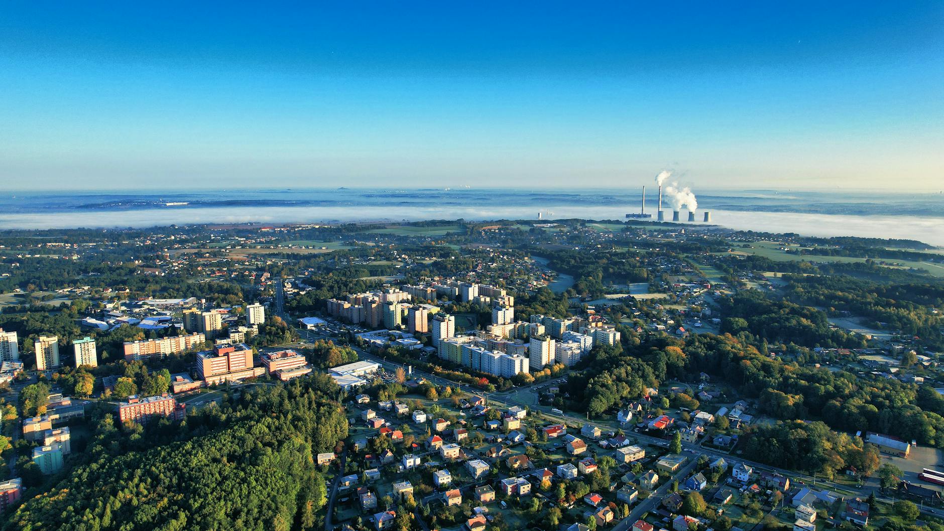 Ilustracja przedstawiająca mapę Oświęcimia z ikonami wskazującymi na jakość powietrza i symbolami zdrowia, związana z frazą 'jakość powietrza Oświęcim'